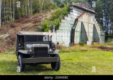 Una storica auto off-Road dell'esercito statunitense si trova di fronte a un ex aeroporto militare. Foto Stock