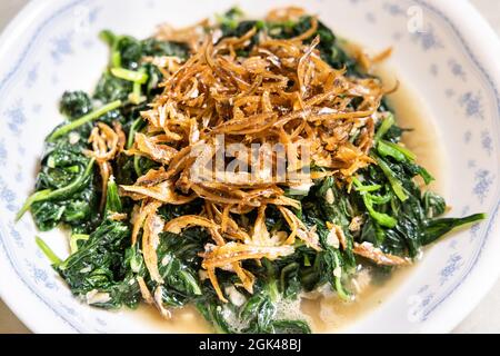 Spicchio di semplice mescolare friggere verdure di spinaci di amaranto verde cinese con aglio, sale e acciughe fritte. Foto Stock