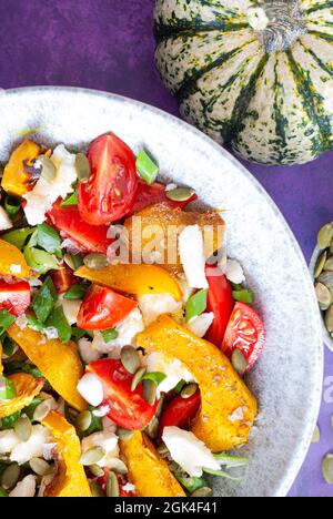 Insalata di zucca con formaggio, semi di zucca e mini pomodori Foto Stock