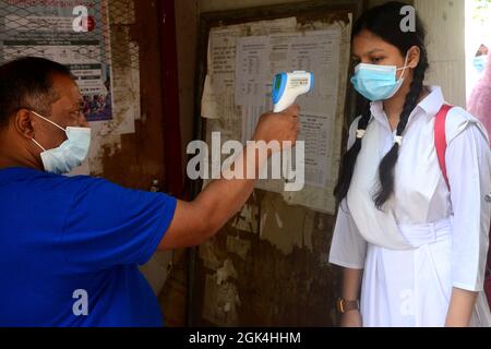 Un funzionario controlla la temperatura corporea di uno studente al suo arrivo alla scuola e al college delle ragazze del governo di Azimpur a Dhaka, Bangladesh, il Sept Foto Stock