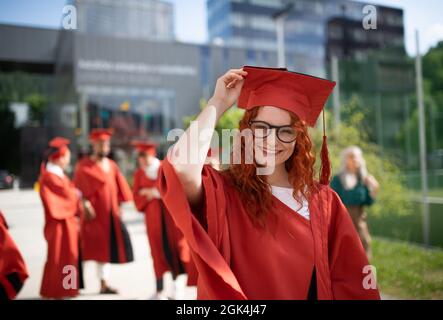 Ritratto di allegro studente universitario che festeggia all'aperto, concetto di laurea. Foto Stock