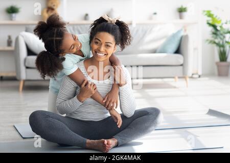 Bella madre nera e figlia coccolare mentre si esercita Foto Stock