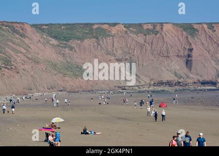 Persone che prendono il sole a Filey Beach, North Yorkshire costa orientale, occupato con vacanzieri, Inghilterra settentrionale, Regno Unito Foto Stock