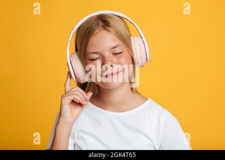 Ritratto di calma cute europea adolescente femmina in bianco t-shirt con occhi chiusi in cuffie wireless ascoltare musica Foto Stock