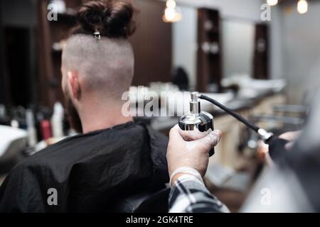Vista posteriore del cliente uomo che visita il centro di ricerca nel barbiere. Foto Stock
