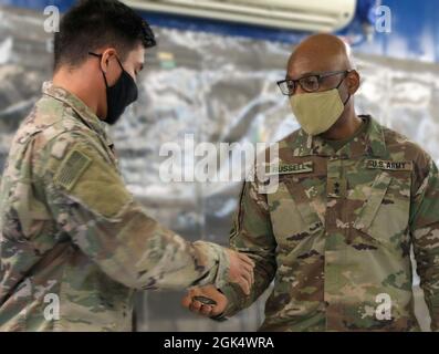 Il primo comando di sostegno al teatro al comando del generale maggiore, il generale Michel M. Russell Sr., presenta la moneta del suo comandante a Pvt. Isidro Guzman, un subacqueo dell'esercito, o 12D, assegnato alla base congiunta Langley-Eustis, Virginia, ha basato 74th il distacco di immersione dell'ingegnere, dopo un briefing al Port Shuaiba, Kuwait, 2 agosto 2021. Guzman ha fornito una breve descrizione dettagliata del modo in cui lui e il suo team ispezionano gli scafi delle navi e le banchine prima dell'inizio delle operazioni. Foto Stock