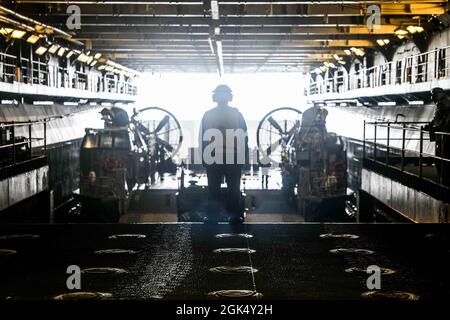 I marinai della marina statunitense assegnati alla nave d'assalto anfibia Wasp-Class USS Kearsarge (LHD 3) dirigono un'imbarcazione da atterraggio, cuscino d'aria (LCAC) nel ponte dei pozzi durante l'esercizio su larga scala 2021 (LSE 2021), a bordo di Kearsarge, 2 agosto 2021. LSE 2021 dimostra la capacità della Marina di impiegare una forza precisa, letale e schiacciante a livello globale in tre comandi di componenti navali, cinque flotte numerate e 17 fusi orari. LSE 2021 unisce le capacità di formazione live e sintetica per creare un ambiente di formazione robusto e intenso. Collegherà la formazione ad alta fedeltà e le operazioni del mondo reale, per costruire il know-owl Foto Stock