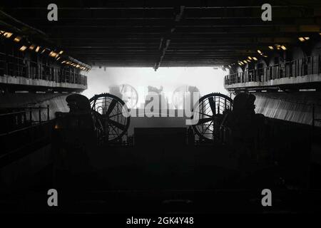 I marinai della marina statunitense assegnati alla nave d'assalto anfibia Wasp-Class USS Kearsarge (LHD 3), dirigono un'imbarcazione da atterraggio, cuscino d'aria (LCAC) nel ponte dei pozzi durante l'esercizio su larga scala 2021 (LSE 2021), a bordo di Kearsarge, 2 agosto 2021. LSE 2021 dimostra la capacità della Marina di impiegare una forza precisa, letale e schiacciante a livello globale in tre comandi di componenti navali, cinque flotte numerate e 17 fusi orari. LSE 2021 unisce le capacità di formazione live e sintetica per creare un ambiente di formazione robusto e intenso. Collegherà la formazione ad alta fedeltà e le operazioni del mondo reale, per costruire il know Foto Stock