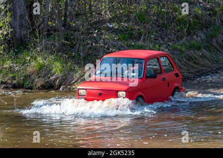 Madona, Lettonia - 01 maggio 2021: La Fiat 126, una vettura rossa a tempo indolo, supera l'ostacolo all'acqua Foto Stock