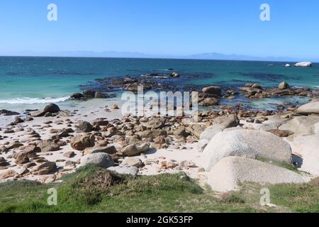 Scenografica acque turchesi dell'oceano Indiano lungo la spiaggia sabbiosa con grandi massi di granito vicino alla città di Simons, sulla Penisola del Capo, Città del Capo, Sudafrica Foto Stock