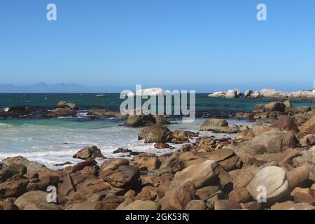 Scenografica acque turchesi dell'oceano Indiano lungo la spiaggia sabbiosa con grandi massi di granito vicino alla città di Simons, sulla Penisola del Capo, Città del Capo, Sudafrica Foto Stock