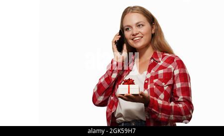 Natale felice sorridente giovane donna tiene confezione regalo e parlare su smartphone isolato su sfondo bianco. Natale, Felice anno nuovo, compleanno conce Foto Stock