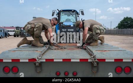 Gli airmen del 2nd Logistics Readiness Squadron si preparano a rimuovere un trattore da un camion a pianale alla base dell'aeronautica di Barksdale, Louisiana, 9 agosto 2021. I professionisti del trasporto a terra dell'aeronautica mantengono i veicoli di base e forniscono le opzioni di trasporto per le varie agenzie di base. Foto Stock