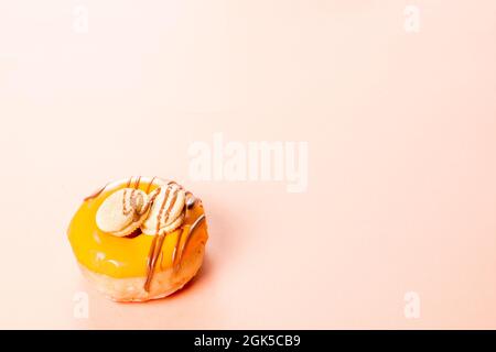 Fotografia di una crema ciambelle decorate con due biscotti e disegnate con cioccolato. La foto è scattata orizzontalmente su uno sfondo color crema.il pho Foto Stock