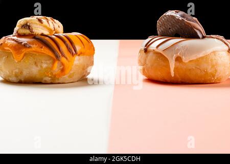 Primo piano di due ciambelle decorate con biscotti e disegnate con cioccolato. La foto è scattata in formato orizzontale e ha spazio per la copia. Foto Stock