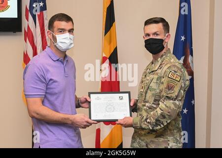 U.S. Air Force Master Sgt. Dennis Owen, responsabile del programma di standardizzazione e valutazioni assegnato al 175esimo Squadrone delle forze di sicurezza, riceve il ritiro delle forze di sicurezza del certificato di badge dal Major. Zachary Blades delle forze di sicurezza degli Stati Uniti, 175esimo comandante Squadron delle forze di sicurezza, in una cerimonia di ritiro di massa presso la base della Guardia Nazionale aerea di Warfield all'Aeroporto di Stato di Martin, Middle River, MD, 7 agosto 2021. A causa dei ritardi subiti dal COVID-19, lo Squadrone delle forze di sicurezza ha tenuto una cerimonia di pensionamento di massa per sei pensionati. Foto Stock