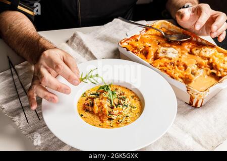 Autentica paella spagnola con merluzzo e cozze. Tradizionale piatto di pesce mediterraneo. Lo chef decora il piatto con le erbe. Piatti del ristorante Foto Stock