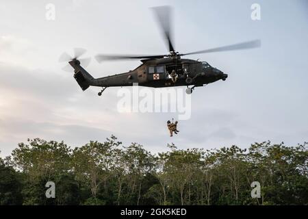 Un paramedico di volo dell'esercito degli Stati Uniti con testa di diamante della forza di operazione, 25th Aviation Regiment ed un medico di combattimento dell'esercito degli Stati Uniti con il guerriero della forza di operazione, sono tirati in su su su su un penetratore della giungla, uno strumento usato per estrarre le vittime ambulatoriali dalle zone pesantemente bosched, all'area di addestramento di Baturaja, Indonesia, il 9 agosto 2021. Garuda Shield 21 è un'esercitazione congiunta di due settimane tra l'esercito degli Stati Uniti e l'Indonesia di Tentara Nasional (TNI-ad Indonesia Armate Forces). Lo scopo di questo esercizio congiunto è quello di migliorare e arricchire la capacità di guerra nella giungla sia dell'esercito degli Stati Uniti che dell'esercito indonesiano. Foto Stock