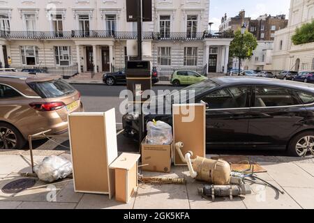 La spazzatura con ribaltabili lasciò illegalmente la strada nella zona di Kensington a Londra, Inghilterra, Regno Unito Foto Stock