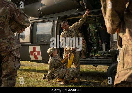 Il personale dell'esercito degli Stati Uniti Sgt. Rios, un paramedico di volo con testa di diamante della Task Force, 25th Aviation Regiment, dà le istruzioni su come azionare un paranco di Blackhawk HH-60 e su come azionare un penetratore della giungla, uno strumento usato per estrarre le vittime ambulatoriali da aree altamente boschive, durante l'addestramento all'area di addestramento di Baturaja, Indonesia, il 9 agosto, 2021. Garuda Shield 21 è un'esercitazione congiunta di due settimane tra l'esercito degli Stati Uniti e l'Indonesia di Tentara Nasional (TNI-ad Indonesia Armate Forces). Lo scopo di questo esercizio congiunto è quello di migliorare e arricchire la capacità di guerra nella giungla sia dell'esercito degli Stati Uniti e. Foto Stock