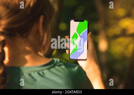 Il giovane escursionista utilizza il telefono cellulare per la navigazione nella foresta, legno sfondo Foto Stock