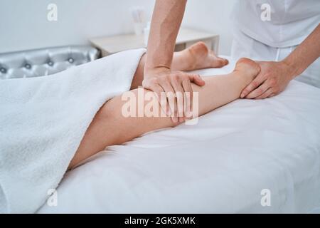 Massoterapista che dà al paziente un massaggio alle gambe Foto Stock