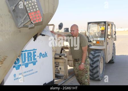 Ingegnere di volo Sgt. Mason Limoni, con B Company, 1 ° battaglione, 171 ° Regiment Aviazione (General Support Battaglione Aviazione), aiuta a caricare il carico su un elicottero CH-47 Chinook Foto Stock