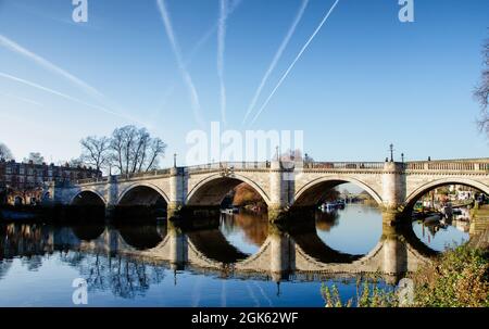 Jet trails dall'aereo che si dirige a Londra Heathrow sopra il ponte di Richmond, riflesso nel Tamigi, Inghilterra Foto Stock