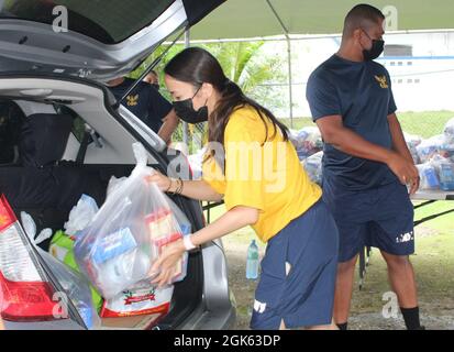 AGAT, Guam (agosto 13, 2021) - i marinai di USS Emory S. Land (AS 39) e Visiting Marines of Combat Logistics Regiment 17 (CLR-17) si sono offerti volontariamente all’Ufficio del Sindaco di Agat per distribuire 400 pacchetti di prodotti alimentari nell’ambito del programma di assistenza alimentare d’emergenza (TEFAP), agosto 12. Le materie prime sono rese possibili attraverso il Guam Department of Education attraverso il Dipartimento dell'Agricoltura degli Stati Uniti Food Nutrition Service e sono distribuite dai sindaci del villaggio a famiglie bisognose e colpite dalla pandemia COVID-19. Il 9 agosto, volontari del Land e CLR 17 hanno confezionato le 400 confezioni di cibo Foto Stock