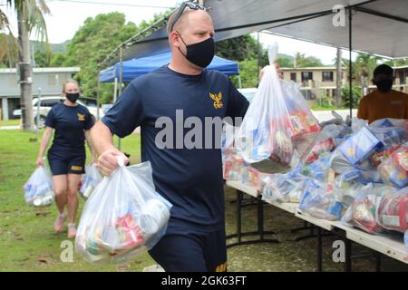 AGAT, Guam (agosto 13, 2021) - i marinai di USS Emory S. Land (AS 39) e Visiting Marines of Combat Logistics Regiment 17 (CLR-17) si sono offerti volontariamente all’Ufficio del Sindaco di Agat per distribuire 400 pacchetti di prodotti alimentari nell’ambito del programma di assistenza alimentare d’emergenza (TEFAP), agosto 12. Le materie prime sono rese possibili attraverso il Guam Department of Education attraverso il Dipartimento dell'Agricoltura degli Stati Uniti Food Nutrition Service e sono distribuite dai sindaci del villaggio a famiglie bisognose e colpite dalla pandemia COVID-19. Il 9 agosto, volontari del Land e CLR 17 hanno confezionato le 400 confezioni di cibo Foto Stock