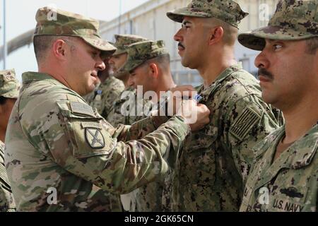 Frank Tantillo, comandante della Task Force Iron Grey, presenta medaglie di conquista dell'esercito a otto marinai della Marina degli Stati Uniti assegnati alla Maritime Expeditionary Security Force Eleven (MSRON-11) durante una cerimonia di premiazione a Camp Lemonnier, Gibuti, 12 agosto 2021. I marinai sono stati assegnati per aver contribuito alla formazione dei soldati dell'esercito degli Stati Uniti attaccati alla Dagger Company, 1-102nd reggimento di fanteria (montagna) su vari compiti come valutazioni di nuoto, tattica lotta contro le vittime e operazioni di base di piccole imbarcazioni. Foto Stock