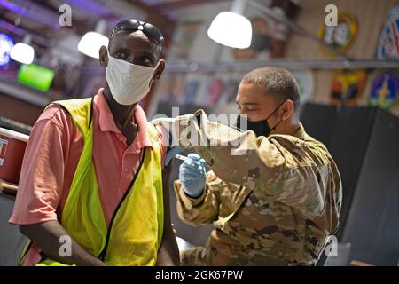 CAMP LEMONNIER, Gibuti (13 agosto 2021) Abdul Falah Yonis Ali, riceve il vaccino COVID-19 da US Air Force Tech Sgt. Kevin Flenoury, di South Boston, Va., durante una somministrazione di vaccino COVID-19 su base, 13 agosto 2021. Camp Lemonnier, Gibuti (CLDJ) funge da base di spedizione per le forze militari statunitensi fornendo supporto a navi, aerei e personale che assicurano la sicurezza in tutta Europa, Africa e Sud-Ovest asiatico. CLDJ permette operazioni marittime e di combattimento nel Corno d'Africa, promuovendo nel contempo relazioni positive tra Stati Uniti e Africa. La base ospita anche attività congiunte combinate Foto Stock