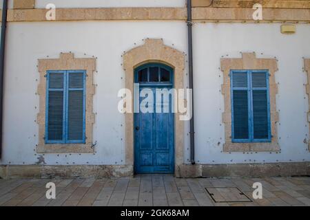 Una porta di legno blu e persiane finestre su un edificio di epoca coloniale a Larnaca, Cipro Foto Stock