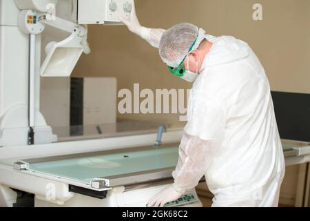 Il medico è in piedi presso l'apparecchio a raggi X. Foto Stock