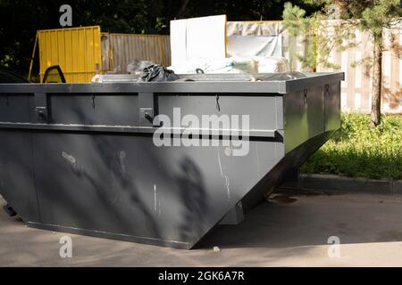 Contenitore per rifiuti di grandi dimensioni. Contenitore dei rifiuti sulla strada. Secchio in metallo verniciato grigio. Punto di raccolta rifiuti per lo smaltimento. Foto Stock