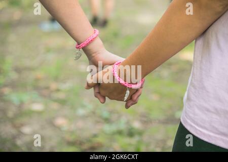 Gioie ragazze che giocano con i compagni nel parco. I bambini tengono le mani sull'erba, si divertono all'aperto e si divertono nel parco. Festa per bambini o. Foto Stock