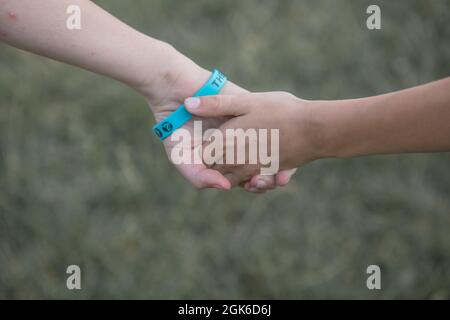 Gioie ragazze che giocano con i compagni nel parco. I bambini tengono le mani sull'erba, si divertono all'aperto e si divertono nel parco. Festa per bambini o. Foto Stock