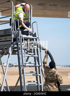 Uno specialista del trasporto aereo Airman dal 2nd Logistics Readiness Squadron consegna un tubo del combustibile ad un membro dell'equipaggio di volo del Boeing 747-8 Freighter alla base dell'aeronautica di Barksdale, Louisiana, 13 agosto 2021. Gli specialisti del trasporto aereo pianificano e organizzano le attività di trasporto aereo, compresa la determinazione delle forniture, delle strutture e del personale necessario. Foto Stock