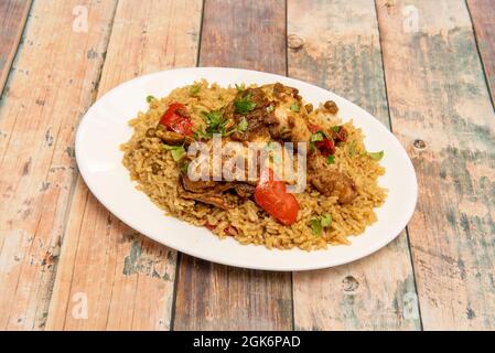 Riso con pollo stufato e verdure saltate, prezzemolo e piselli cotti in un ristorante peruviano su tavola di legno. Foto Stock