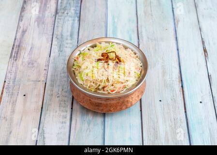 Tradizionale ciotola in metallo indiano con riso pilau nel ristorante pakistano su sfondo di legno Foto Stock