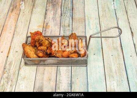 Ali fritte con salsa di chimichurri in un cestino di metallo per immergere in olio d'oliva bollente Foto Stock