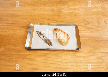Deliziosa tapa di acciuga cantabrica spagnola accompagnata da pane tostato su un vassoio di metallo Foto Stock