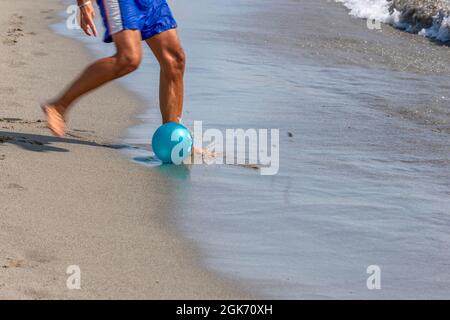 Le gambe di un uomo che gioca a calcio sulla riva della spiaggia di Marina di Carrara, Toscana, Italia Foto Stock