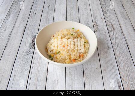 Ciotola bianca di riso tre delizie cucinate in un ristorante cinese con tavoli bianchi Foto Stock