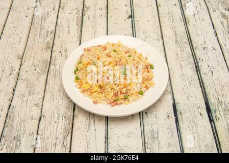 Tre delizie di riso con prosciutto a dadini, omelette, piselli verdi e carote su un piatto bianco Foto Stock