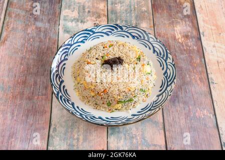 Portando tre delizie di riso ad un altro livello con verdure e uova fritte condite e cosparse di tartufo nero all'interno di un bel piatto Foto Stock