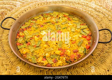 Paella di verdure spagnole con sfondo vimini Foto Stock