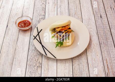 bao di pollo fritto in stile giapponese con rucola, pomodoro, cipolla rossa e salsa a parte Foto Stock