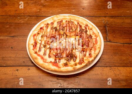 Pizza al barbecue di dimensioni individuali con fette di bacon fritte, mince stufata e mozzarella con salsa Foto Stock