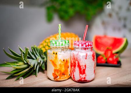 Frullati di frutta in vasetti di vetro con paillette. Frullato alla fragola e alla passione Foto Stock